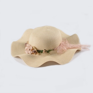 Beige wide brim straw sun hat with decorative floral accents and ribbon for summer beach