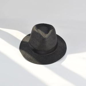 Top view of a black paper straw jazz hat with ribbon, detailed texture and shadow effect