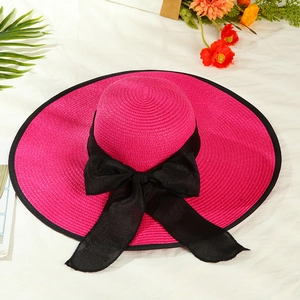 Detailed texture of rose red straw hat with black bow for sun protection and summer travel