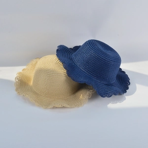 Detail of woven straw sun hats with wavy edges in beige and navy blue colors