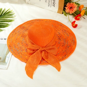 Detail of orange wide brim straw hat with multi-color dots and a large bow for summer travel