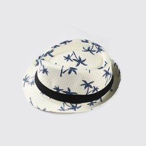 Detail of cream straw fedora hat featuring blue coconut tree patterns and a black ribbon band