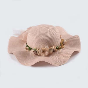 Fashionable pink straw sun hat with wide wavy brim and elegant floral bow decoration
