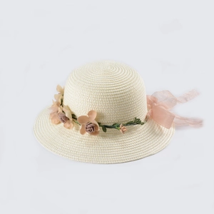 Dettaglio di un cappello di paglia con fiori in tessuto rosa e nastro in organza