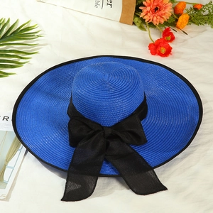 Close-up of woven straw texture and navy blue brim with black ribbon bow on sun hat