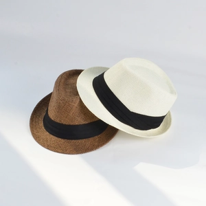 Detail view of woven textures on brown and beige fedora straw hats with black ribbons
