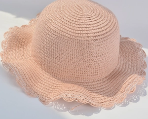Detailed macro view of pink straw sun hat with woven texture and white lace wavy edge
