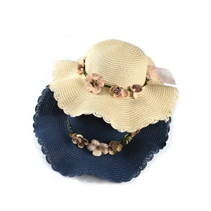 Detail of wide-brim straw sun hats with floral ribbon and lace edge for beach vacation