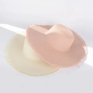 Detail shot of wide brim straw sun hats with fringe edges and natural sunlight shadows