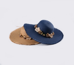 Detail view of summer straw hats with frayed edges and decorative fabric flowers