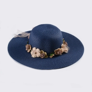 Close-up of navy straw sun hat with woven texture, fabric flowers and sheer tulle ribbon