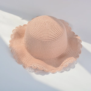 Detail of light pink woven straw sun hat with decorative wavy brim and spiral pattern