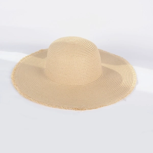 Detail of high-density straw weave texture and frayed fringe edges on wide brim sun hat
