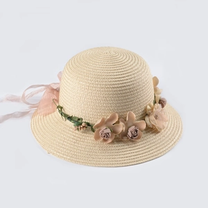 Dettaglio cappello di paglia con ghirlanda floreale e nastro di chiffon rosa