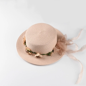 Detail view of woven boater hat featuring floral garland and organza bow with long ribbons