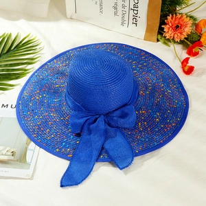 Close-up of royal blue straw hat featuring colorful speckles and large mesh bow decoration