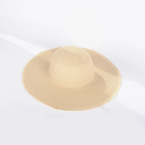 Close-up of beige straw sun hat showing fine woven texture and frayed fringe edge detail