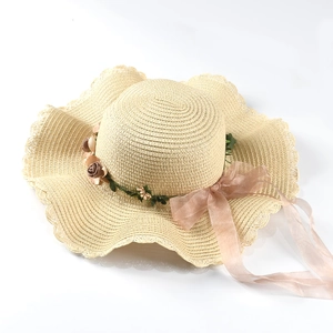 Detailed macro view of beige wide-brim straw hat with decorative silk flowers and organza ribbon