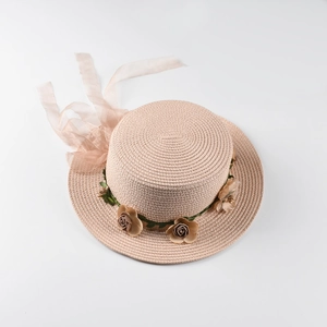 Detail of boater straw hat featuring 3D floral garland and elegant long mesh ribbon