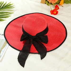 Detail of red straw sun hat with large black mesh bow and elegant woven texture