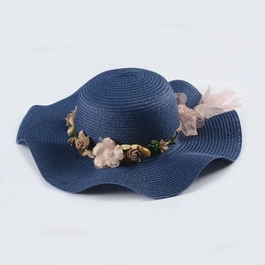 Detailed top view of navy blue straw sun hat with wavy brim and floral lace embellishment