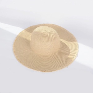 Close-up of beige straw sun hat featuring a stylish fringed brim and woven texture