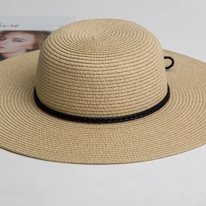 Wide brim straw hat with black woven band on white background, stylish sun protection