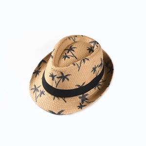 Close-up of woven straw texture and black tropical coconut tree prints on kids fedora