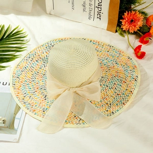 Detail of wide brim straw hat with floral pattern and delicate beige mesh bow