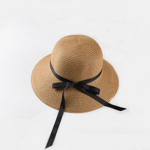 Detail of woven straw sun hat with textured pattern and elegant black ribbon bow