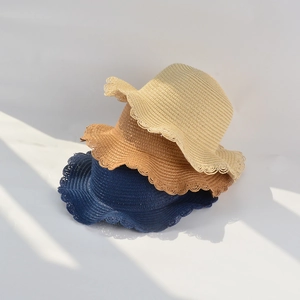 Detail of straw sun hats with scalloped lace edges in beige, brown and navy blue