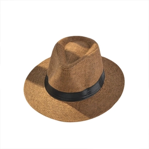 Classic brown straw fedora beach hat with black ribbon decoration on white background
