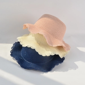 Close-up of wavy brim straw hats in pink, beige and navy colors for summer sun protection