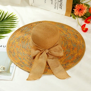 Summer wide brim straw sun hat with colorful speckles and bow on beach vacation background