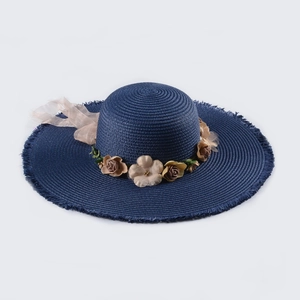 Detail of navy straw sun hat featuring handcrafted floral decor and fringed edge