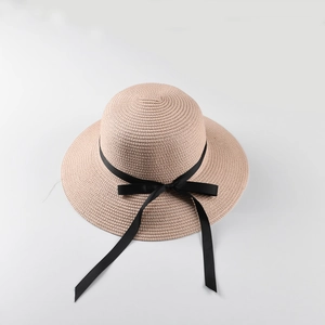 Detail of light pink woven straw sun hat featuring a black satin ribbon bow
