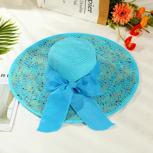 Close-up of blue straw hat with floral accents and a large bow on a beachy set