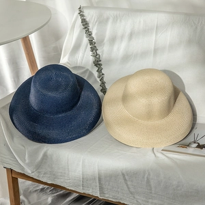 Detailed texture of navy and beige woven straw sun hats on a soft background