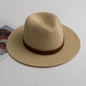 Detail of straw Panama hat with dark brown leather decorative band on a white surface