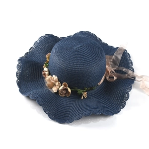 Detail of navy woven sun hat featuring wide wavy brim and elegant floral silk ribbon