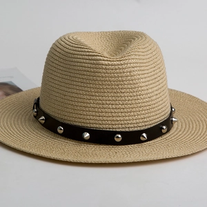 Classic straw Panama hat with black faux leather punk studded band on grey background