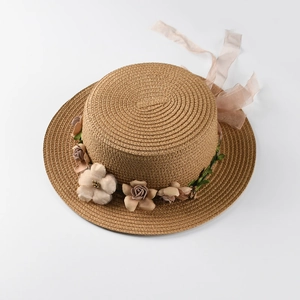 Detail of woven boater hat featuring realistic fabric flowers and soft chiffon ribbons