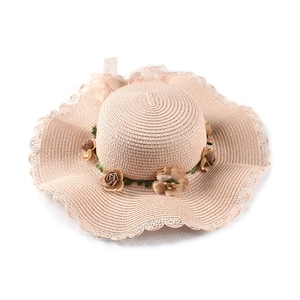 Close-up of pink wide brim straw hat with handmade fabric flowers and ribbon bow detail