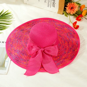 Close-up of bright pink straw sun hat with large mesh bow and decorative brim weave