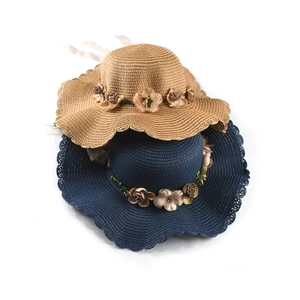 Close-up of wide-brim woven straw hats with floral trim in brown and navy blue colors