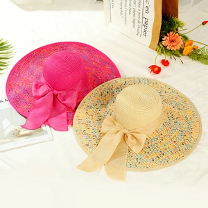 Detail of wide brim straw hats with colorful ribbon bows in rose red and beige tones