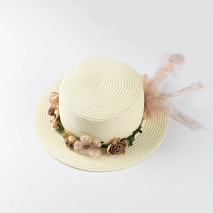 Detail of cream straw hat with floral wreath and light pink chiffon ribbon for sun protection