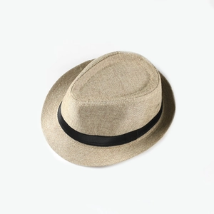 Close-up of woven linen texture and black ribbon detail on beige summer Fedora hat