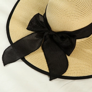 Detailed macro view of summer straw hat with oversized black ribbon bow and fine texture