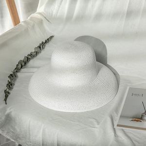 Close-up of fine woven white straw hat with wide brim on minimalist fabric background